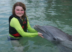 Wish kid Alice swims with dolphins during her wish trip.